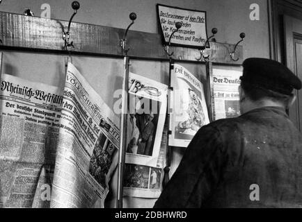 'Besides books, the reading hall also offers the latest newspapers and magazines. Above the newspaper hooks there is a sign saying: ''The reading room is not a place for loud talking, for playing cards, for quarrelling and scuffling''. Below this are the newspapers, among others: Rheinisch-Westfaelische Zeitung, Voelkischer Beobachter, Illustrierter Beobachter, (cover picture: Adolf Hitler with Paul Ludwig Troost) and Die Brenessel.' Stock Photo