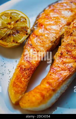 Salmon steak cooked on grill for dinner in seafood restaurant.Gourmet red fish grilled with lemon fruits Stock Photo