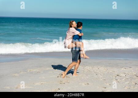 Side view boyfriend carrying girlfriend beach Stock Photo