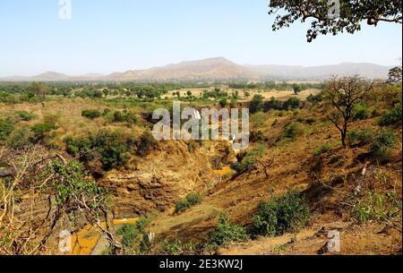 The slender Blue Nile Falls tumble into a narrow gorge cutting through the surrounding plains near Bahir Dar, Ethiopia, beneath a pale blue sky. Stock Photo