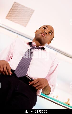 Low angle view of a young man leaning against a bar counter Stock Photo