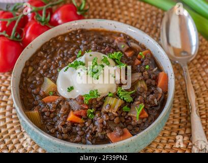 Stew with beluga lentils, vegetables and sour cream topping served in a bowl from above with spoon Stock Photo