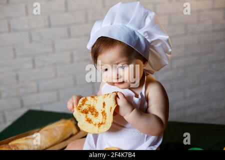 Little chef. Little kid dressed as a chef with pastries, buns, bread Stock Photo