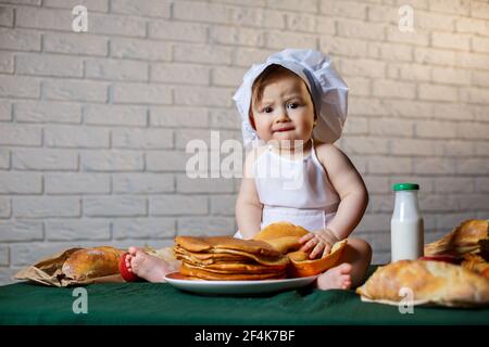 Little chef. Little kid dressed as a chef with pastries, buns, bread Stock Photo