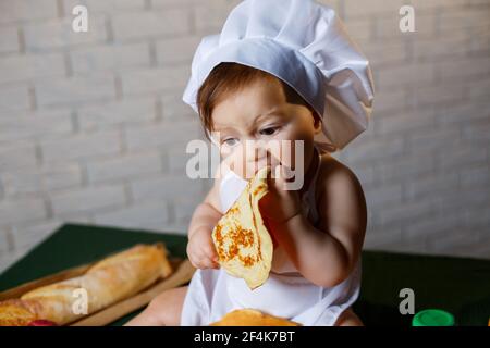 Little chef. Little kid dressed as a chef with pastries, buns, bread Stock Photo