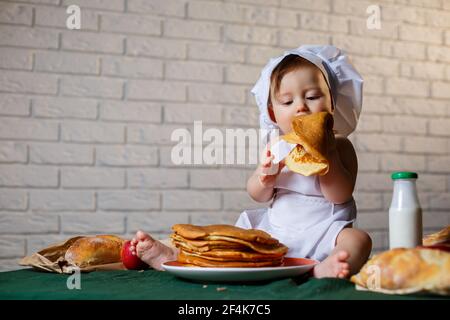 Little chef. Little kid dressed as a chef with pastries, buns, bread Stock Photo