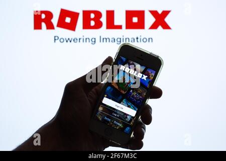 In this photo illustration, the Roblox app seen displayed on a smartphone screen and a Roblox logo in the background. Stock Photo