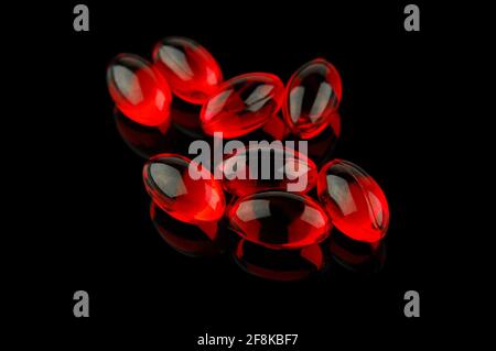 Red vitamin pills on black background. Selective focus limited to front pills. Stock Photo