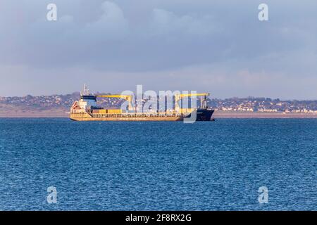 General Cargo Ship at Southend Anchorage on Thames Estuary off Shoeburyness with Kent Shore in Background with Rising Sun Illuminating Hull Stock Photo