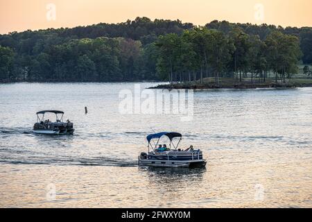 Families relaxing on pontoon boats at sunset on Lake Lanier along the shores of Lake Lanier Islands resort complex in North Georgia. (USA) Stock Photo