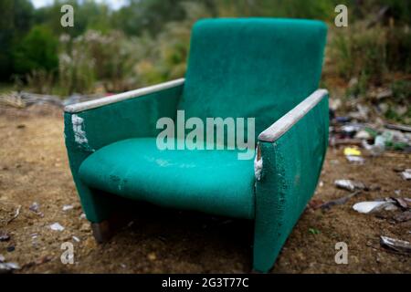 The old chair is in a landfill. Abandoned wasteland with waste and garbage. Stock Photo