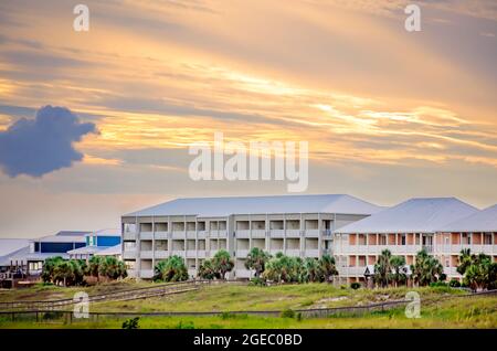 The sun sets behind condominiums on Dauphin Island’s west end, Aug. 12, 2021, in Dauphin Island, Alabama.The island is vulnerable to climate change. Stock Photo