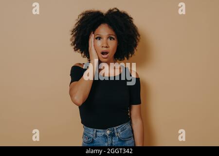 Studio portrait of young shocked african female with unexpected facial expression Stock Photo