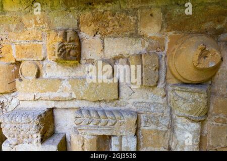 Fragments of the carved stonework from Hailes Abbey imbedded in the wall of St Peter’s church graveyard next to Stanway House, Cotswolds, England Stock Photo