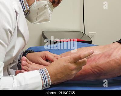 The doctor performs sclerotherapy on varicose veins in the legs, In the hospital a doctor performs treatment with varicose vein, injection. Stock Photo