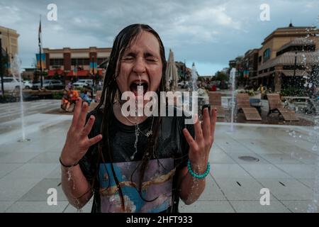 Surprised teen girl playing in fountain outside Stock Photo