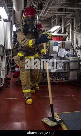 PHILIPPINE SEA (Jan. 29, 2022) Fireman Brandon Arreola, from San Diego, assigned to the forward-deployed amphibious assault ship USS America (LHA 6), simulates putting out hot embers in the ship’s main engine room during a machinery space firefighting drill. America, lead ship of the America Amphibious Ready Group, along with the 31st Marine Expeditionary Unit, is operating in the U.S. 7th Fleet area of responsibility to enhance interoperability with allies and partners and serve as a ready response force to defend peace and stability in the Indo-Pacific region. (U.S. Navy photo by Mass Commun Stock Photo