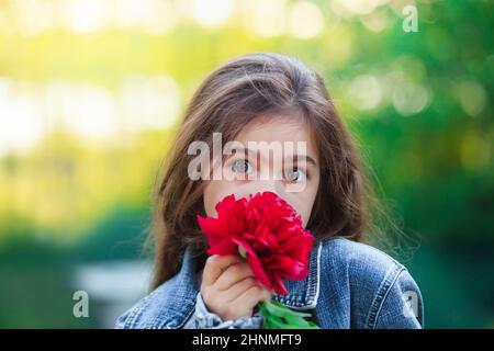 Surprised Little cute girl with peony flowers. Child  playing in summer garden. Kids gardening. Children with flower bouquet for birthday or mother s Stock Photo