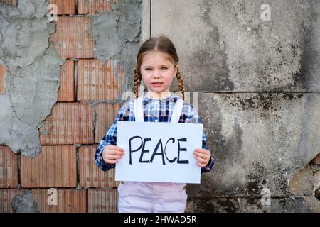 Child girl holding a poster with written PEACE in support of peace. Concept of 'no war' in Ukraine and in the world. Russian conflict Stock Photo