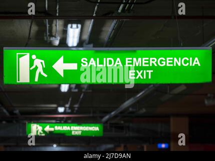 Illuminated emergency exit sign, in Spanish and English. Stock Photo