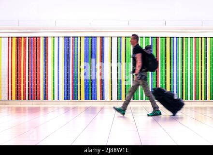 Motion blur of man walking at international airport with suitcase and backpack - Concept of alternative lifestyle traveling around the world Stock Photo