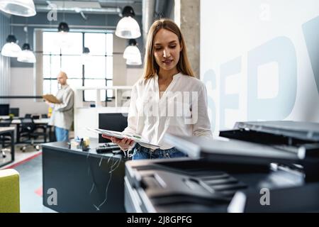 Young employee using modern printer in office Stock Photo