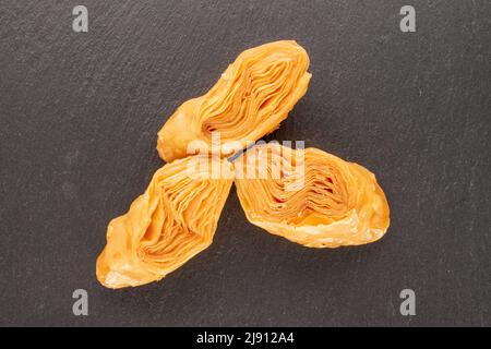 Three pieces of sweet honey baklava on a slate stone, close-up, top view. Stock Photo