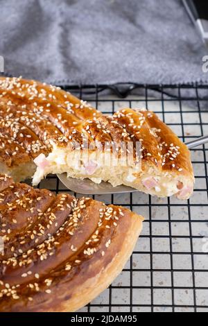 Homemade burek rolled pie with cheese, ham and sesame. Selective focus. Stock Photo