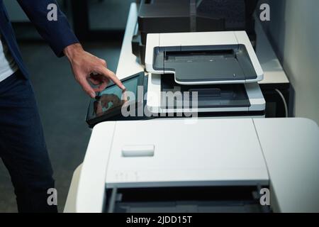 Person in office using printer and pressing on its screen Stock Photo