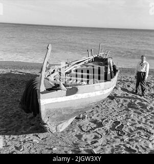 41. Spain. Photo journal is available at B.M.A. + Photo albums. Acquisition: Books and archive materials. Photos taken 1959-11-12.12 Pictures in series. According to notes: Spain. S. Mediterranean coast, Castell de Ferro, 12/11-59. Old -fashioned boat on the beach. One stands looking at a boat that is commissioned on a sandy beach. Stock Photo