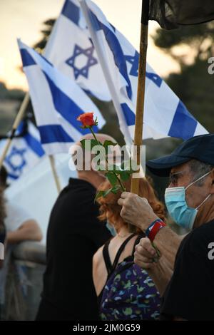 A senior man wearing a sanitary mask holding a red rose during a protest in Jerusalem, Israel Stock Photo