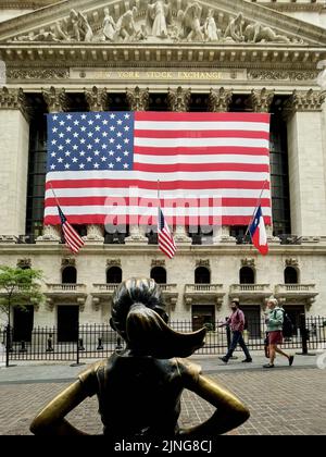 Fearless Girl statue from the back with the New York Stock Exchange in the background.  Located in the Financial District in New York City, USA. Stock Photo