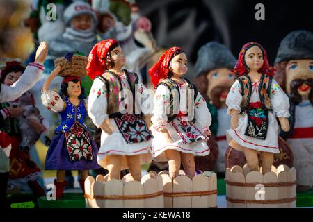 Assortment of clay Souvenirs in traditional moldovan suits. Souvenir clay figurines of women trample grapes in wooden skating rinks. Moldavian folk ar Stock Photo