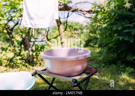 Hand washing clothes in a basin outside in summer Stock Photo