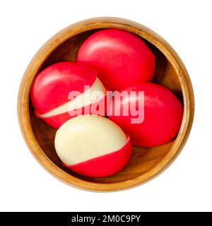 Snack cheese disks in red wax encasements, in a wooden bowl. Small edam slices, each one encased in a blend of red colored paraffin. Stock Photo