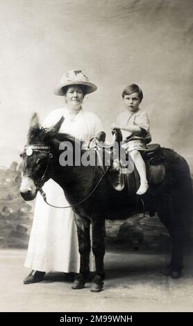 Young Boy and his Mother - Studio photo, with the young lad seated on a rather care-worn donkey! Stock Photo