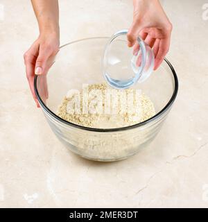 Adding cold water to suet crust pastry mixture in mixing bowl Stock Photo