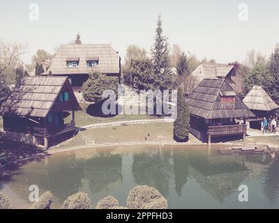 Stanisici, Bijelina, Bosnia and Herzegovina. April 25, 2021 Ethno-village, traditional village houses made of logs, Bosnian style of construction in the highlands. Lake with water.Wooden architecture. Stock Photo