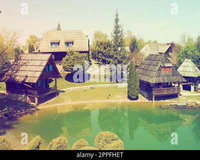 Stanisici, Bijelina, Bosnia and Herzegovina. April 25, 2021 Ethno-village, traditional village houses made of logs, Bosnian style of construction in the highlands. Lake with water.Wooden architecture. Stock Photo