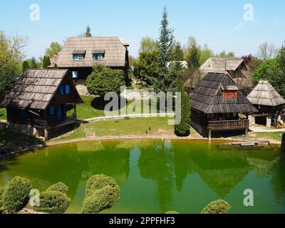 Stanisici, Bijelina, Bosnia and Herzegovina. April 25, 2021 Ethno-village, traditional village houses made of logs, Bosnian style of construction in the highlands. Lake with water.Wooden architecture. Stock Photo