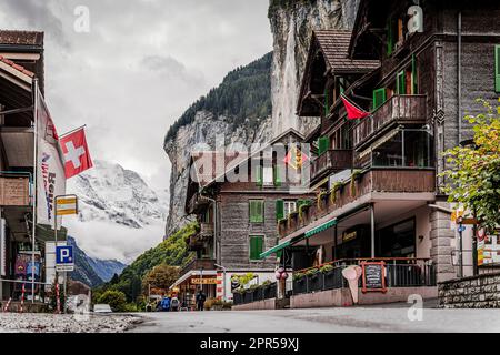 Traditional wood houses in the alpine village of Lauterbrunnen with Trummelbach Falls on background, Bern canton, Switzerland Stock Photo