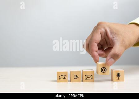 Hand holding wood cube block icon communication internet network service and website email on table concept. Stock Photo