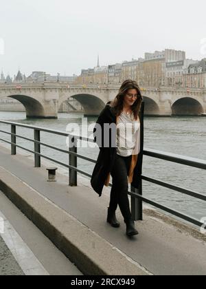 American woman walks along the Seine River in Paris Stock Photo