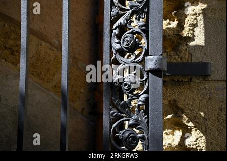 Antique hand crafted wrought iron entrance gate against a stone wall in Cefalù Sicily, Italy. Stock Photo