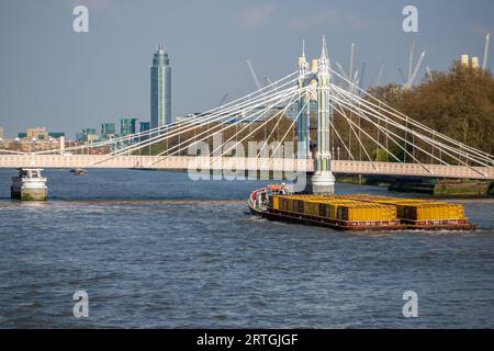 Barges towed by a tugboat on the River Thames at Albert Bridge Stock Photo