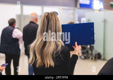 Meeting at the airport, person holding a placard card sign with welcome title text, greeting passenger on arrival, holding a name plate to greet trave Stock Photo