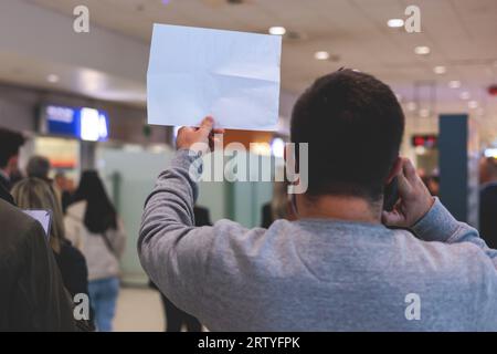 Meeting at the airport, person holding a placard card sign with welcome title text, greeting passenger on arrival, holding a name plate to greet trave Stock Photo