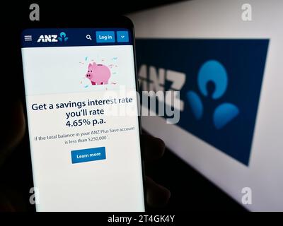 Person holding smartphone with web page of Australia and New Zealand Banking Group Limited (ANZ) with logo. Focus on center of phone display. Stock Photo