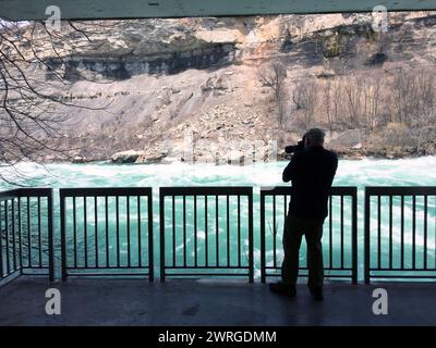 A photographer takes photos along Niagara River just below Niagara Falls on the White Water Walk, a popular Niagara Parks attraction. Stock Photo