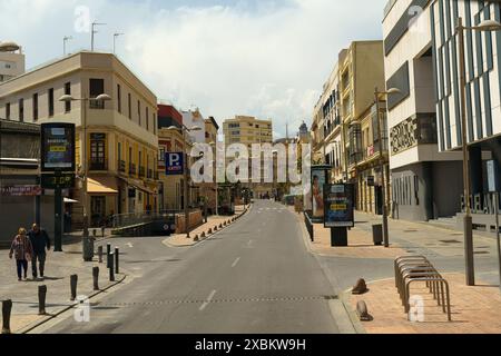 Almeria, Spain - May 25, 2023: An empty street in Almeria, Spain on a sunny day. The street is lined with buildings and there are a few streetlights a Stock Photo